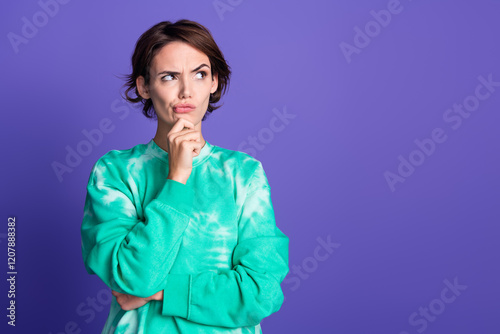 Photo of attractive young woman touch chin skeptical look empty space dressed stylish green clothes isolated on violet color background photo