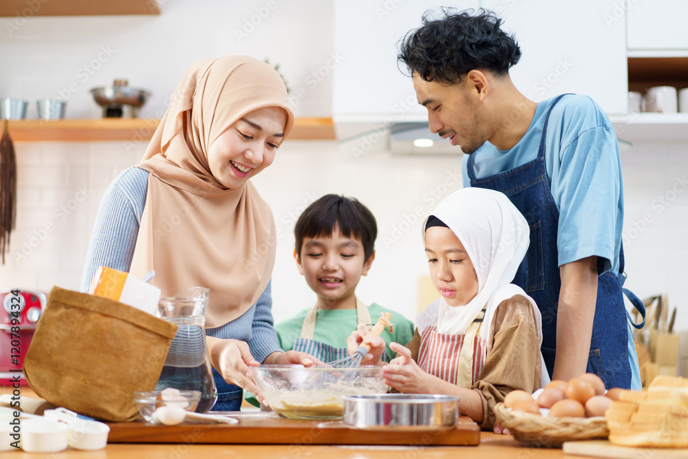 Happy Asian muslim family consisting father, mother, son, and daughter are cooking together in the kitchen. Happy Asian muslim family consisting father, mother, son, and daughter are cooking together in the kitchen.