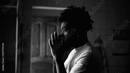 Profile of a devout young black man in PRAYER at home in monochromatic. Artistic black and white clip of religious African American person asking for God's intervention
