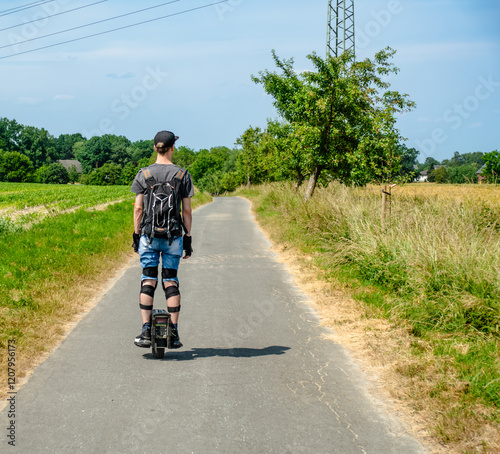 A man is riding a electric unicycle euc on a country road