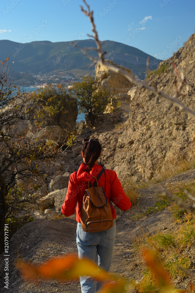 female traveler in a yellow jacket with a backpack travels to the mountains, fresh air