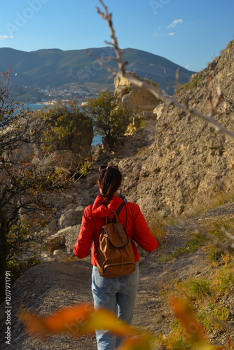 female traveler in a yellow jacket with a backpack travels to the mountains, fresh air