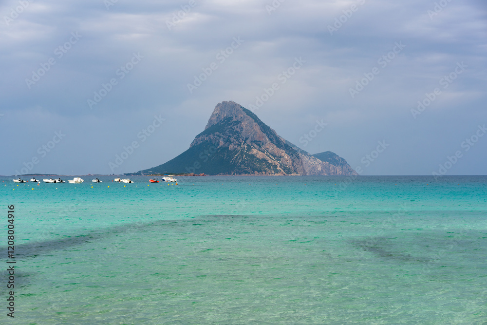 Tavolara island seen from Porto Taverna beach with turquoise water on a cloudy day in Sardinia, Italy