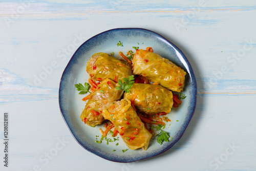 Stuffed cabbage leaves. Cabbage wraps or rolls. Chou farci, dolma, sarma, golubtsy or golabki on blue plate on green blue table. High angle view