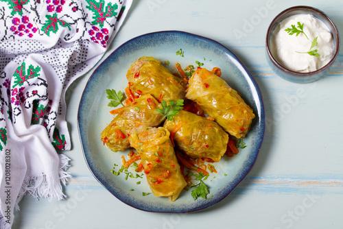 Stuffed cabbage leaves. Cabbage wraps or rolls. Chou farci, dolma, sarma, golubtsy or golabki on blue plate on green blue table. High angle view photo