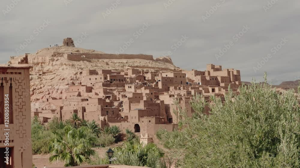 The fortified village of Ait Benhaddou stands tall against the Moroccan sky. This ancient ksar, a UNESCO World Heritage site, showcases traditional Berber architecture. Tourists explore The fortified village of Ait Benhaddou stands tall against the Moroccan sky. This ancient ksar, a UNESCO World Heritage site, showcases traditional Berber architecture. Tourists explore