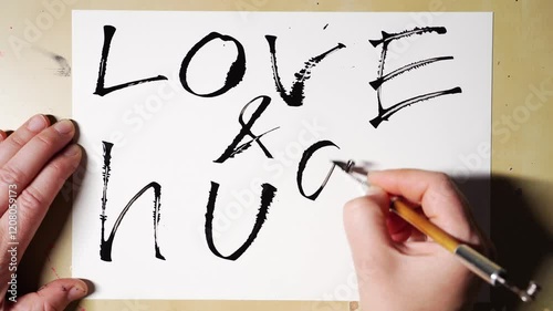 Hands creating calligraphy love message with brush love and hugs art sequence.