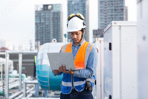 Male engineer work using laptop computer for checks or maintenance in sewer pipes area at construction site. Male plumber working in sewer pipes area at rooftop of building