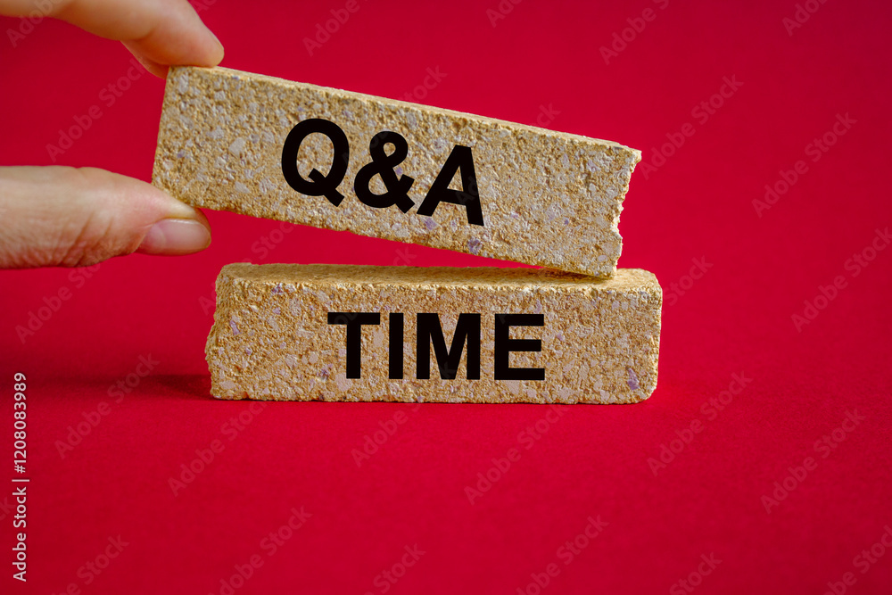 Q and A, questions and answers time symbol. Concept words 'Q and A time' on brick blocks. Businessman hand. Beautiful red background. Business and Q and A time concept.