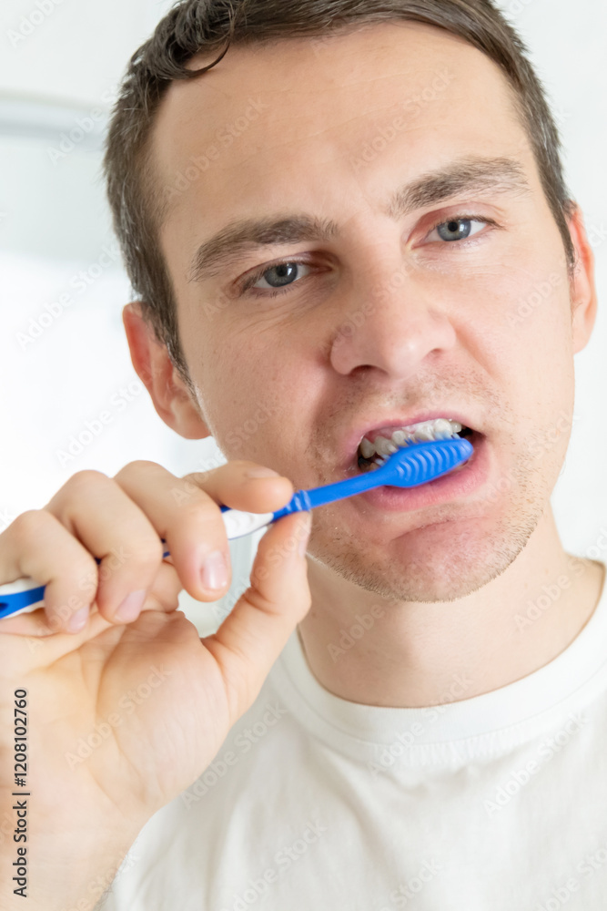 Young man brushing teeth with toothbrush at home in the bathroom Young man brushing teeth with toothbrush at home in the bathroom
