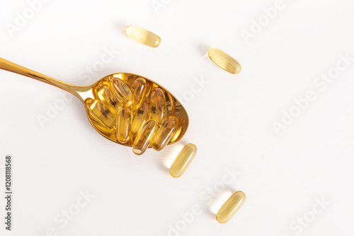 Yellow vitamins in golden spoon on white background. Omega 3. Biologically active additive photo