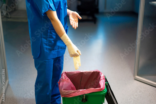 hospital nurse disposing of used gloves in biological container photo