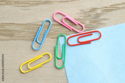 Many colorful clips and paper notes on wooden table, flat lay