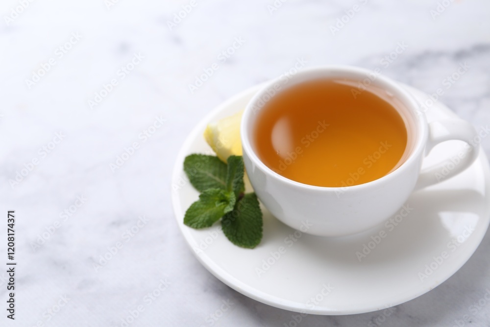 Aromatic mint tea in cup, fresh leaves and lemon on light table, closeup. Space for text Aromatic mint tea in cup, fresh leaves and lemon on light table, closeup. Space for text