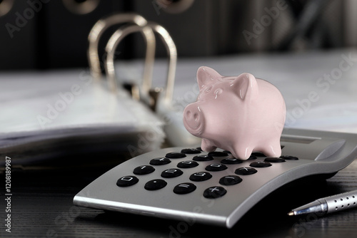 Mini piggy bank on calculator next to folders on desk, calculate income and expenses to save money or make investments for the future, finance saving concept photo