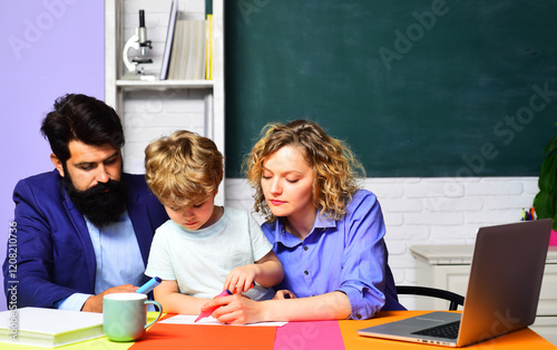 Private lesson. Cute boy from elementary school doing schoolwork with male and female teachers. Educational process and learning. Teachers helping kid from primary school in classroom doing homework.