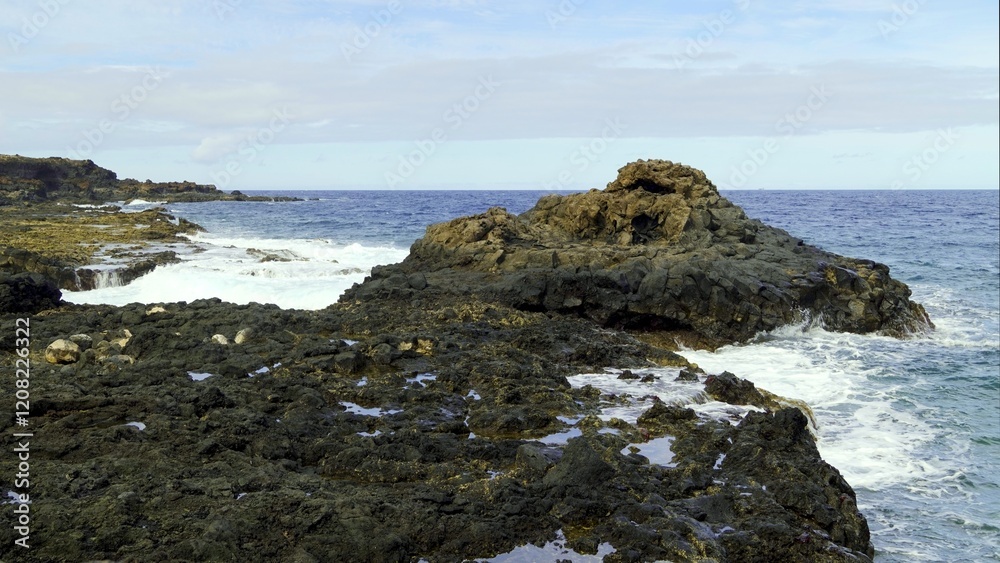 Ocean waves crashing against black volcanic rocks on the coast of Charco del Palo in Lanzarote, Canary Islands, Spain, creating a dramatic seascape under a cloudy sky Ocean waves crashing against black volcanic rocks on the coast of Charco del Palo in Lanzarote, Canary Islands, Spain, creating a dramatic seascape under a cloudy sky