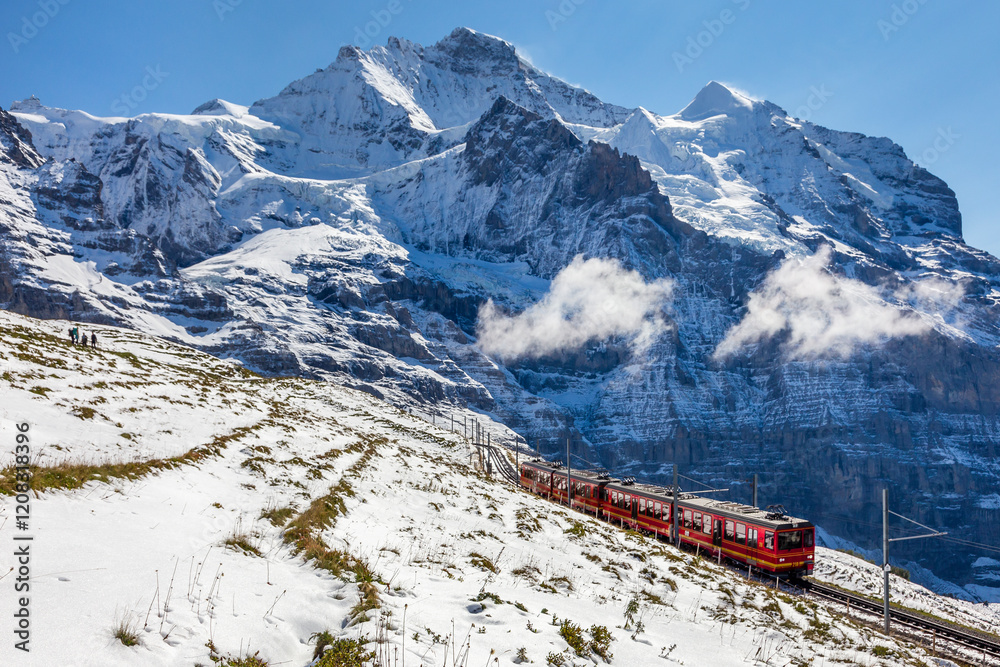 Obraz premium Sunny winter day, the train between Jungfraujoch (Top of Europe) and Kleine Scheidegg on the snowy hillside with Jungfrau in background
