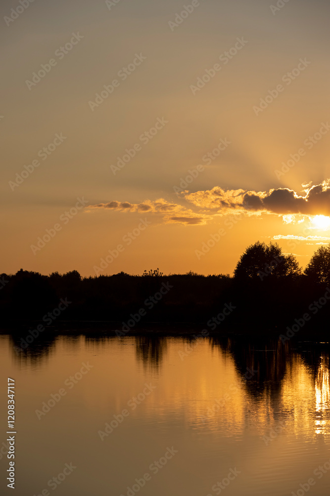 Naklejka premium beautiful orange sunset on the river in summer is reflected in the water