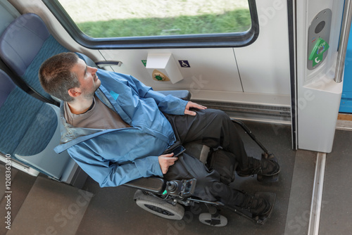 Young wheelchair user traveling by train, watching a landscape through the window. Disability, mobility, and accessibility concepts. photo