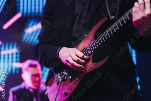 Concert view of an electric guitar player with vocalist and rock band performing in a club, male musician guitarist on stage with audience in a crowded concert club hall arena, hands on a guitar photo