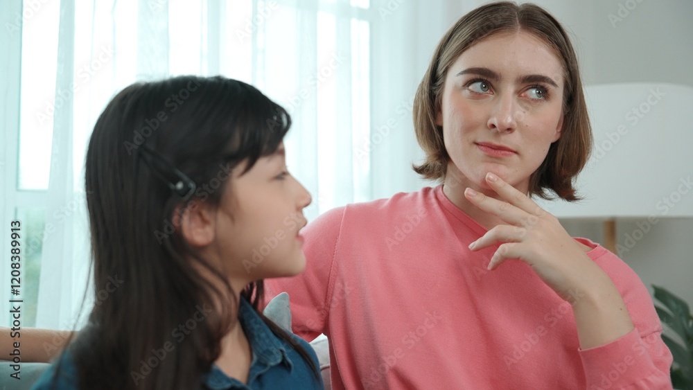 Happy mother sharing experience with daughter while sitting in living room. Caucasian mom and happy child talking and spend time together. Attractive girl listen parent story while smiling. Pedagogy. Happy mother sharing experience with daughter while sitting in living room. Caucasian mom and happy child talking and spend time together. Attractive girl listen parent story while smiling. Pedagogy.