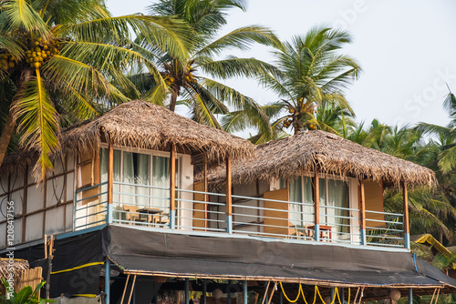 Tropical beach huts with thatched roofs surrounded by lush palm trees,