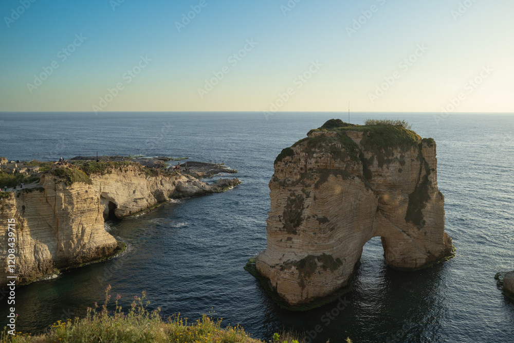 Fototapeta premium The sunset behind Raouche Rock in Lebanon, casting a stunning glow over the Mediterranean waters. Travel blogs, postcards, and tourism advertisements, social media content.