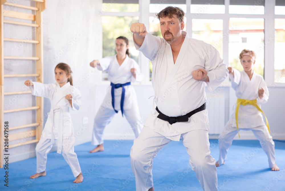 Family of karatekas with two children practicing karate techniques in gym Family of karatekas with two children practicing karate techniques in gym