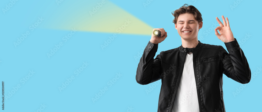 Young man with flashlight showing OK on blue background Young man with flashlight showing OK on blue background