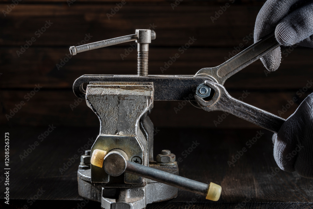 Mechanic in a workshop using a vice unscrews a nut with wrenches, closeup. Using old spanner wrench and clamp to remove nut from bolt. Work of a worker at a workplace Mechanic in a workshop using a vice unscrews a nut with wrenches, closeup. Using old spanner wrench and clamp to remove nut from bolt. Work of a worker at a workplace