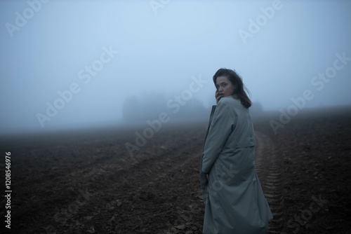 Obraz na płótnie gloomy woman in coat walks alone in foggy field, existential crisis w salonie
