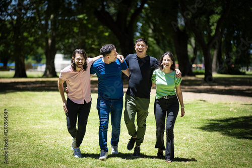 Group of latin friends walking arm in arm in a park under a bright sun