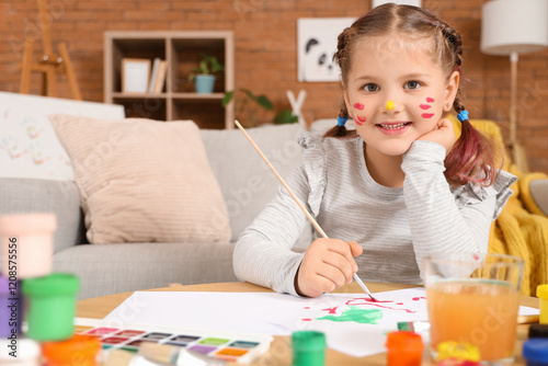 Little girl painting on table at home