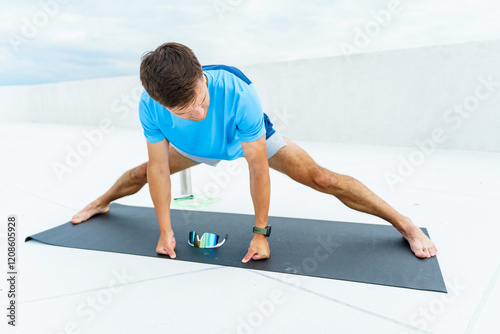 Yoga practice on a rooftop during daytime with a person doing a side stretch on a black mat photo