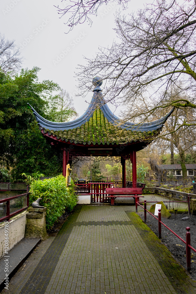 A picturesque Asian-style pavilion with a green-tiled roof surrounded by lush greenery in a tranquil garden. A picturesque Asian-style pavilion with a green-tiled roof surrounded by lush greenery in a tranquil garden.