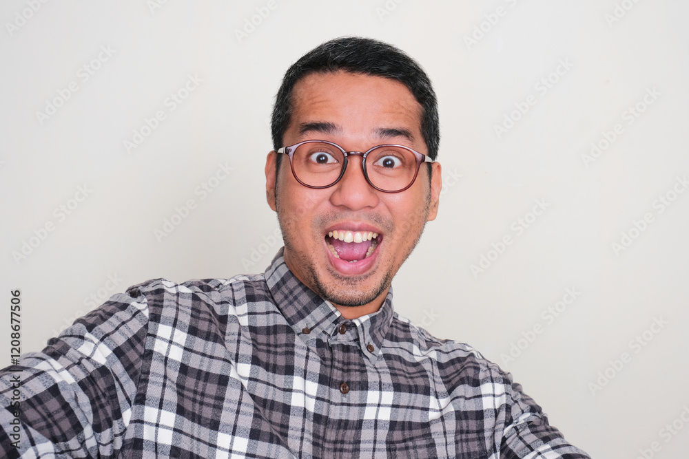 Adult Asian man doing selfie shot with excited face expression Adult Asian man doing selfie shot with excited face expression