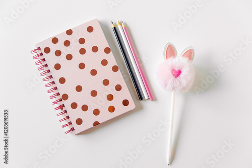 Stylish flat lay, beautiful women's notebook in polka dots, cute fluffy pen and pencils. feminine background, copy space