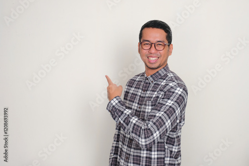 Adult Asian man smiling happy while pointing behind him photo