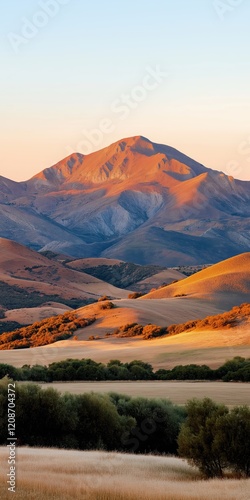 Golden hour mountain landscape with warm sunlight illuminating rolling hills and natural beauty for mobile wallpaper