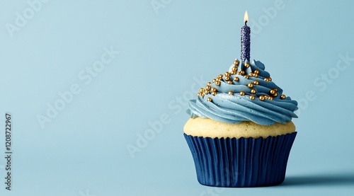 Single blue cupcake with gold sprinkles and lit candle on blue background.