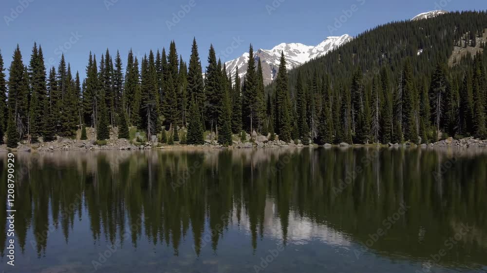 Mountain lake surrounded by pine trees and snowy peaks, reflecting nature's tranquility, serene landscape photography Mountain lake surrounded by pine trees and snowy peaks, reflecting nature's tranquility, serene landscape photography