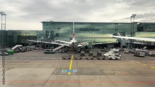 Luggage train vehicle drive on airport with airplane docked at Frankfurt Airport with bustling activity