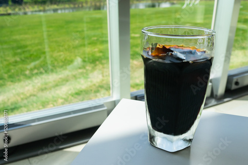 Obraz na płótnie キレイな風景が見えるカフェ。氷が入ったアイスコーヒー。 w salonie