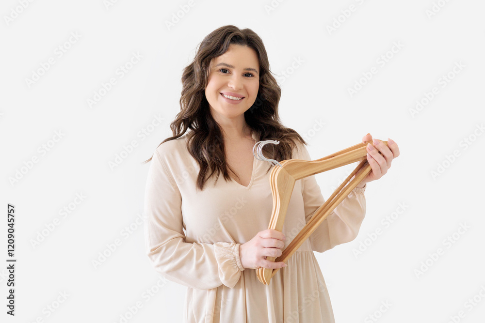 Young beautiful girl in beige dress holds several empty wooden clothes hangers Young beautiful girl in beige dress holds several empty wooden clothes hangers