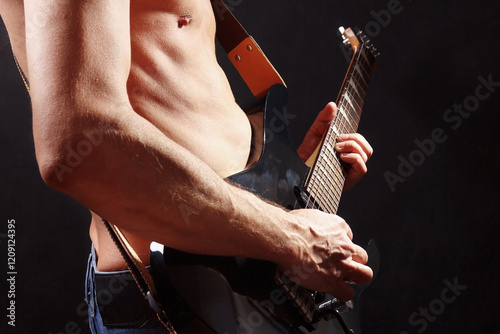 Rock guitarist playing solo on black guitar on dark stage.