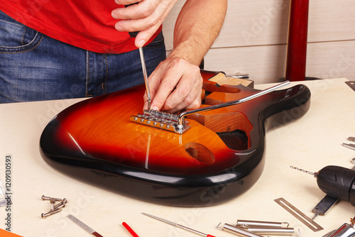Guitar repairer screws tremolo into the body of guitar.