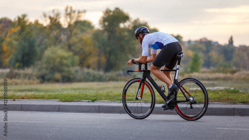 Bicyclist riding on a road at sunset in a serene landscape Bicyclist riding on a road at sunset in a serene landscape