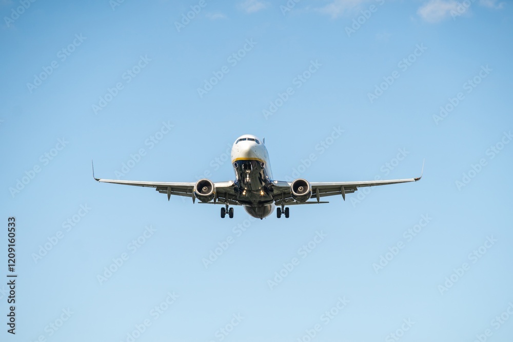 Commercial airplane approaches landing during clear sky with minimal clouds in the background