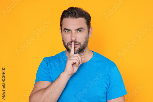 Man with finger on lips. Silence gesture. The Shh. Portrait of man showing silence sign isolated on yellow background. Shh man. Hush shut silent Concept. Mute and quiet, finger on mouth shush sign.